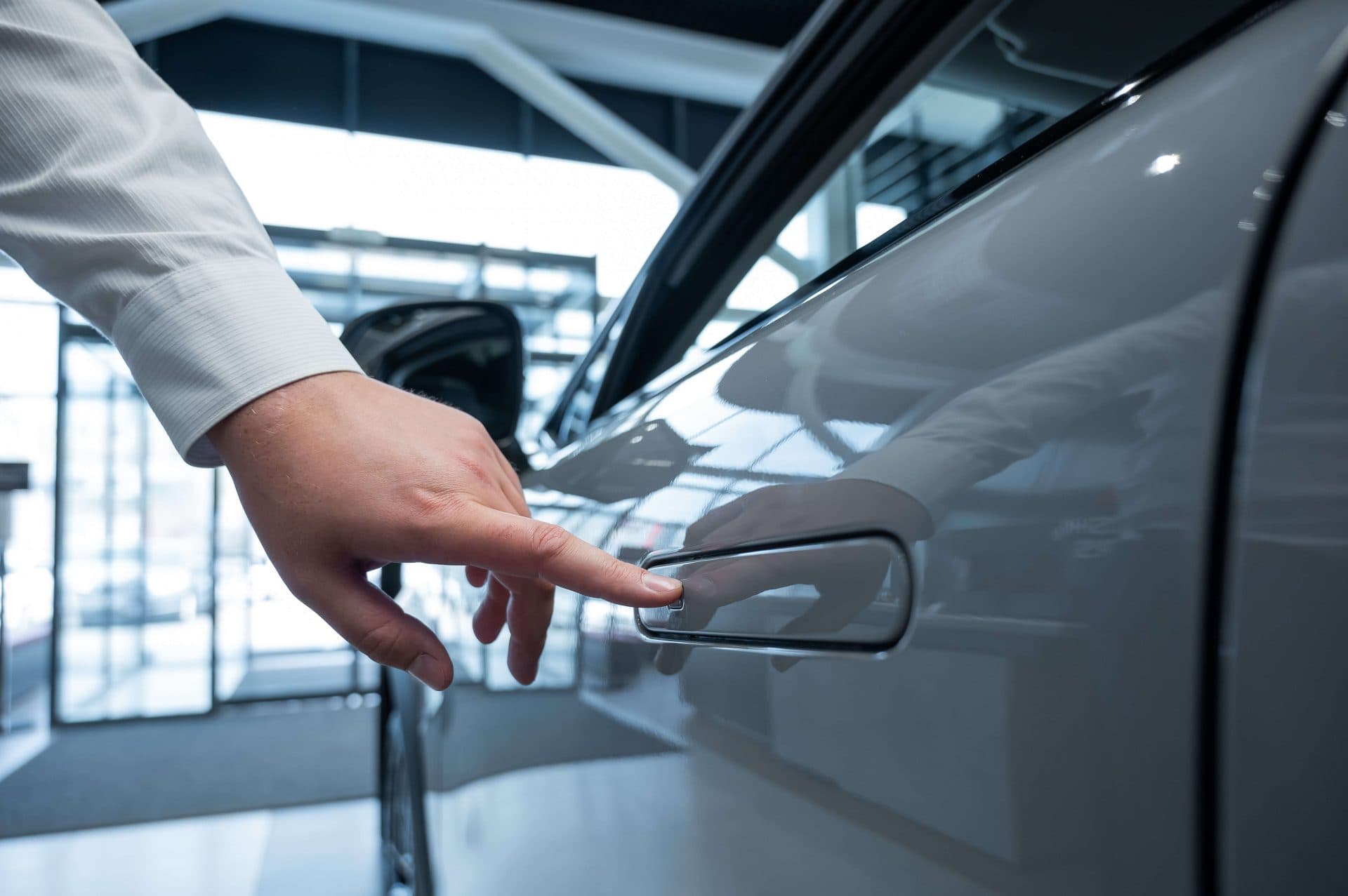Hand reaching for a flush door handle on a modern car